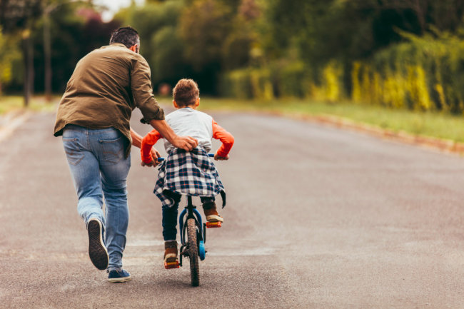man helping his kid in learning to ride a bicycle picture id1140118229 t 650x433